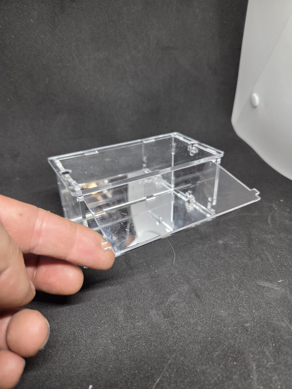 Hand sliding out the removable mirror base panel of the KF003-M single display case